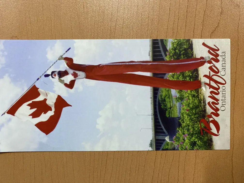 Doug Hunt on stilts in a Canada Day costume holding a Canadian flag